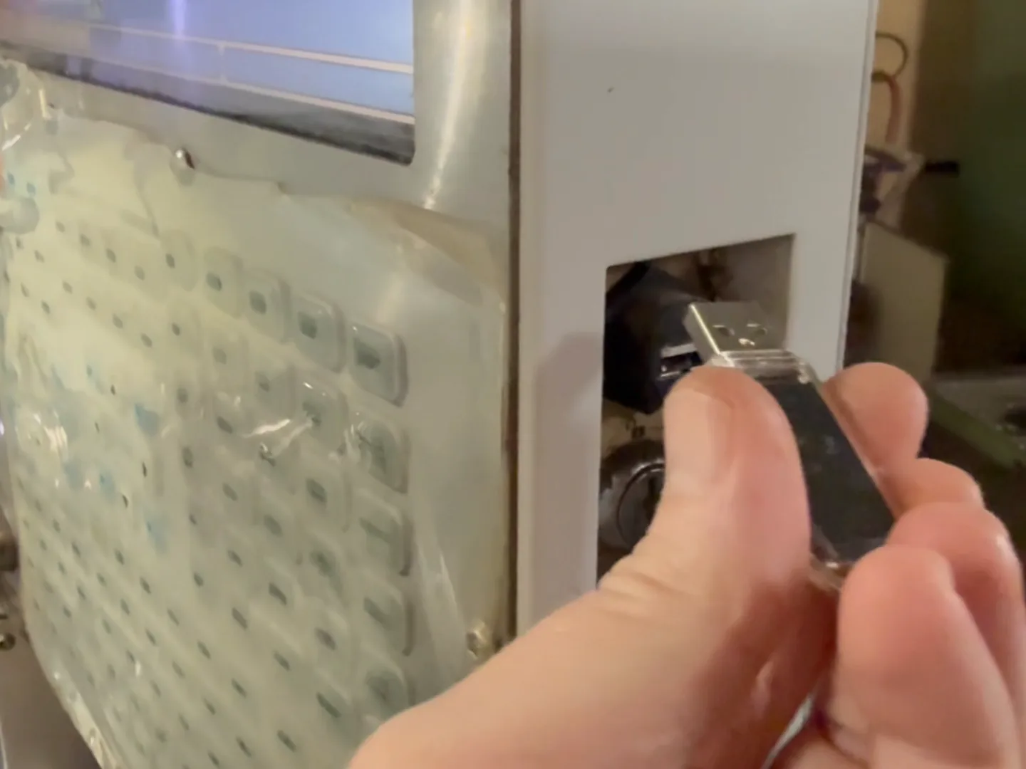 A hand plugging a WiFiDrive into a Haas pendant’s side port