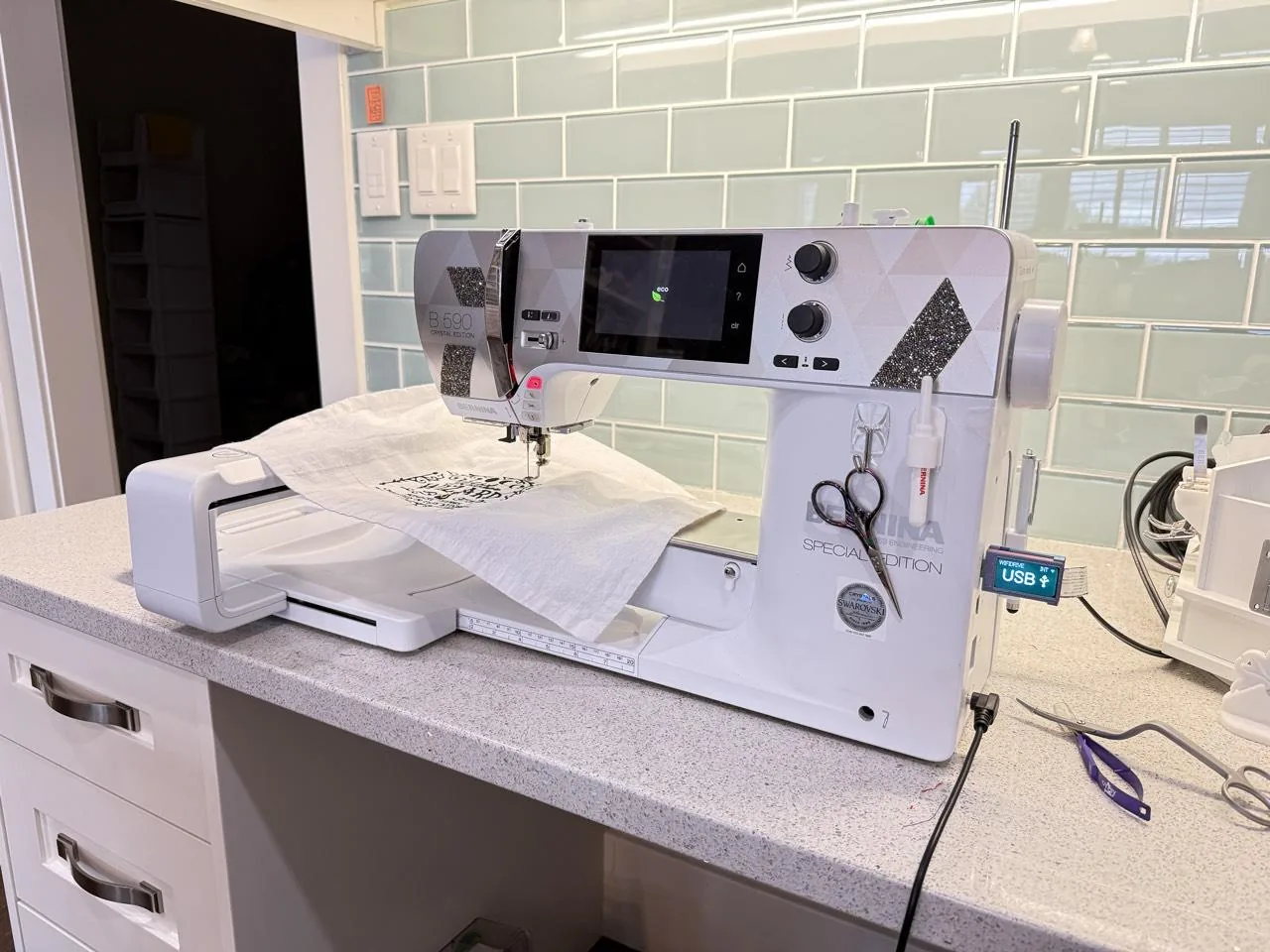 A Bernina B 590 Crystal Edition with its embroidery module and a design embroidered on the fabric, the WiFiDrive in USB mode in its USB port on the right