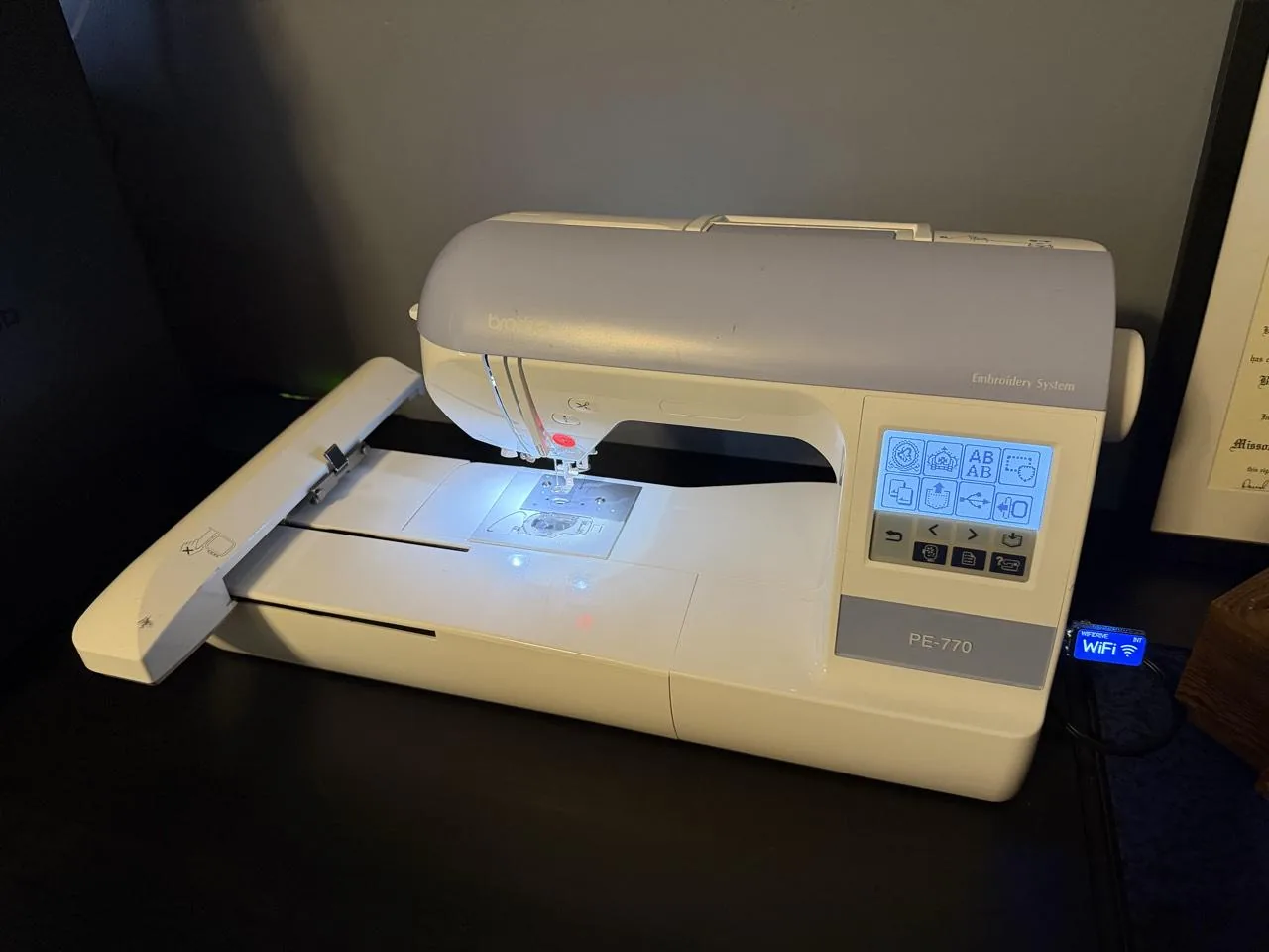 A Brother PE770 with the WiFiDrive in its USB port, the drive's screen showing WiFi mode on the internal volume and the embroidery screen open