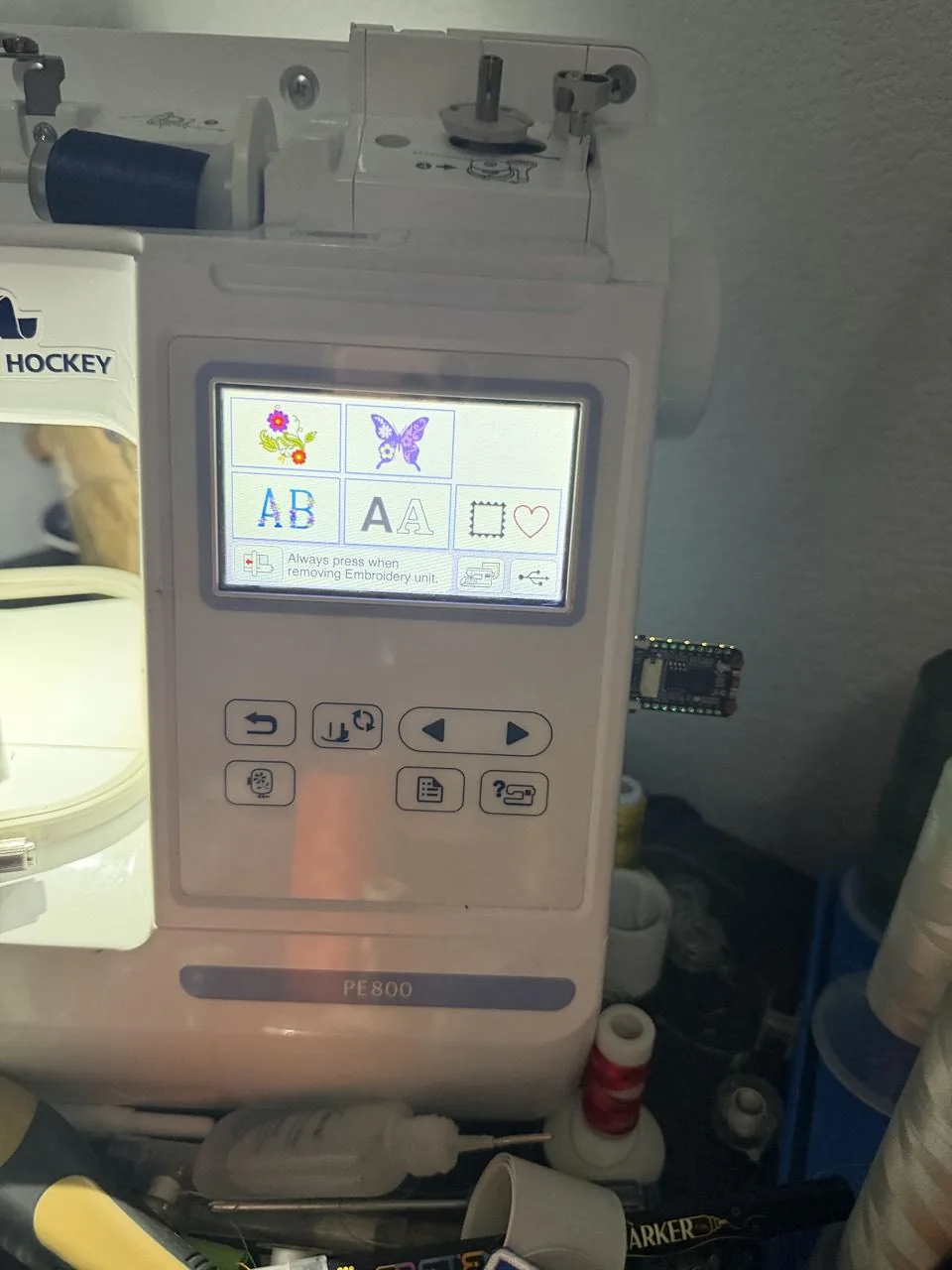 A Brother PE800's control panel with a bare WiFiDrive board in its USB port, the embroidery screen open