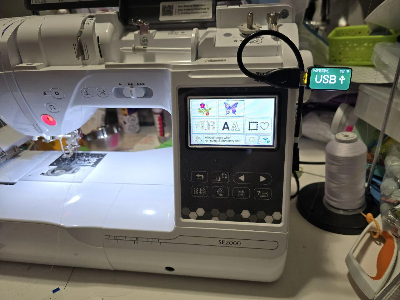A Brother SE2000 with the WiFiDrive in USB mode on a short extension cable in its USB port, the embroidery screen open