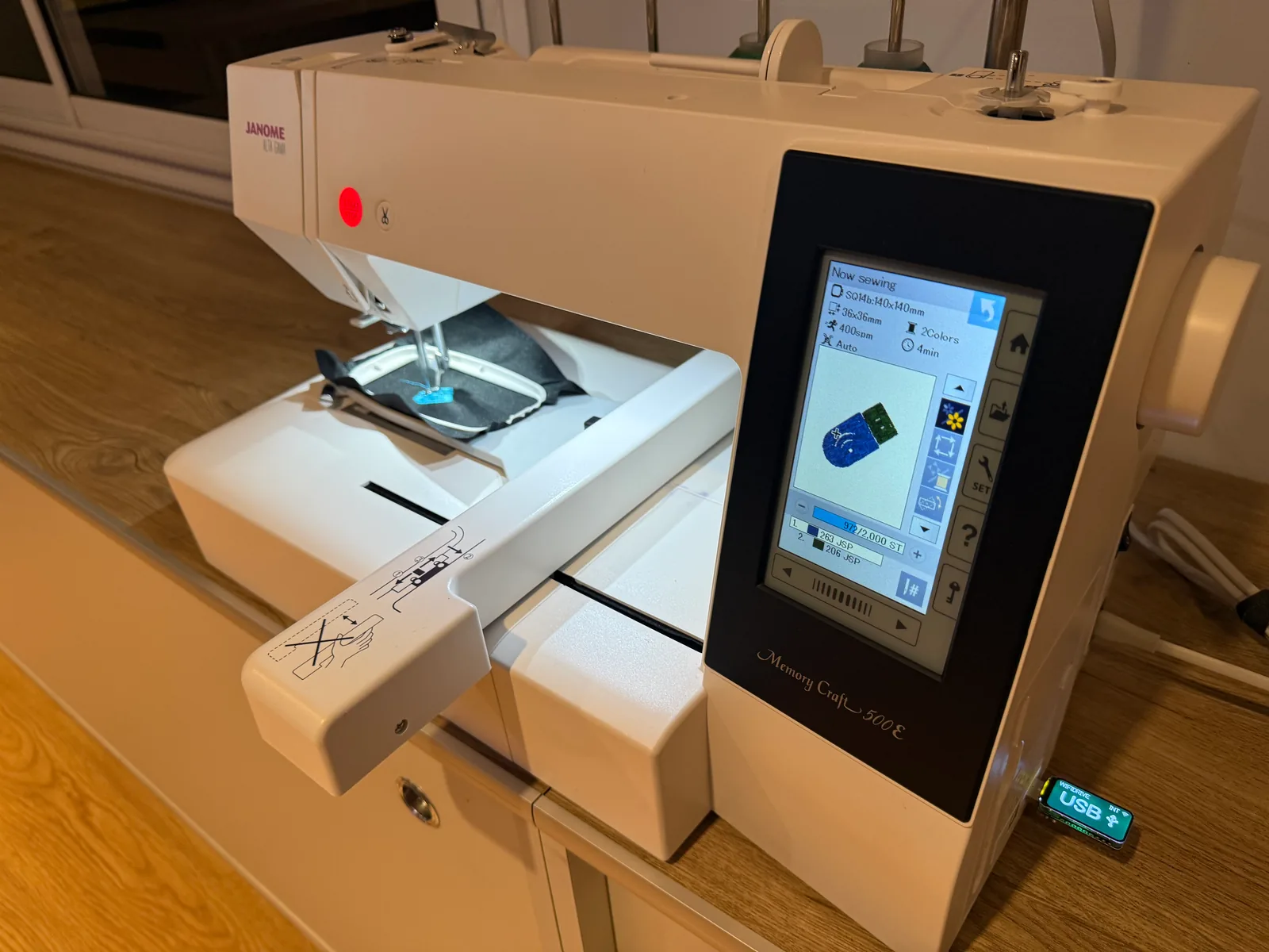 A Janome Memory Craft 500E sewing a design of the WiFiDrive, read from the WiFiDrive in its USB port