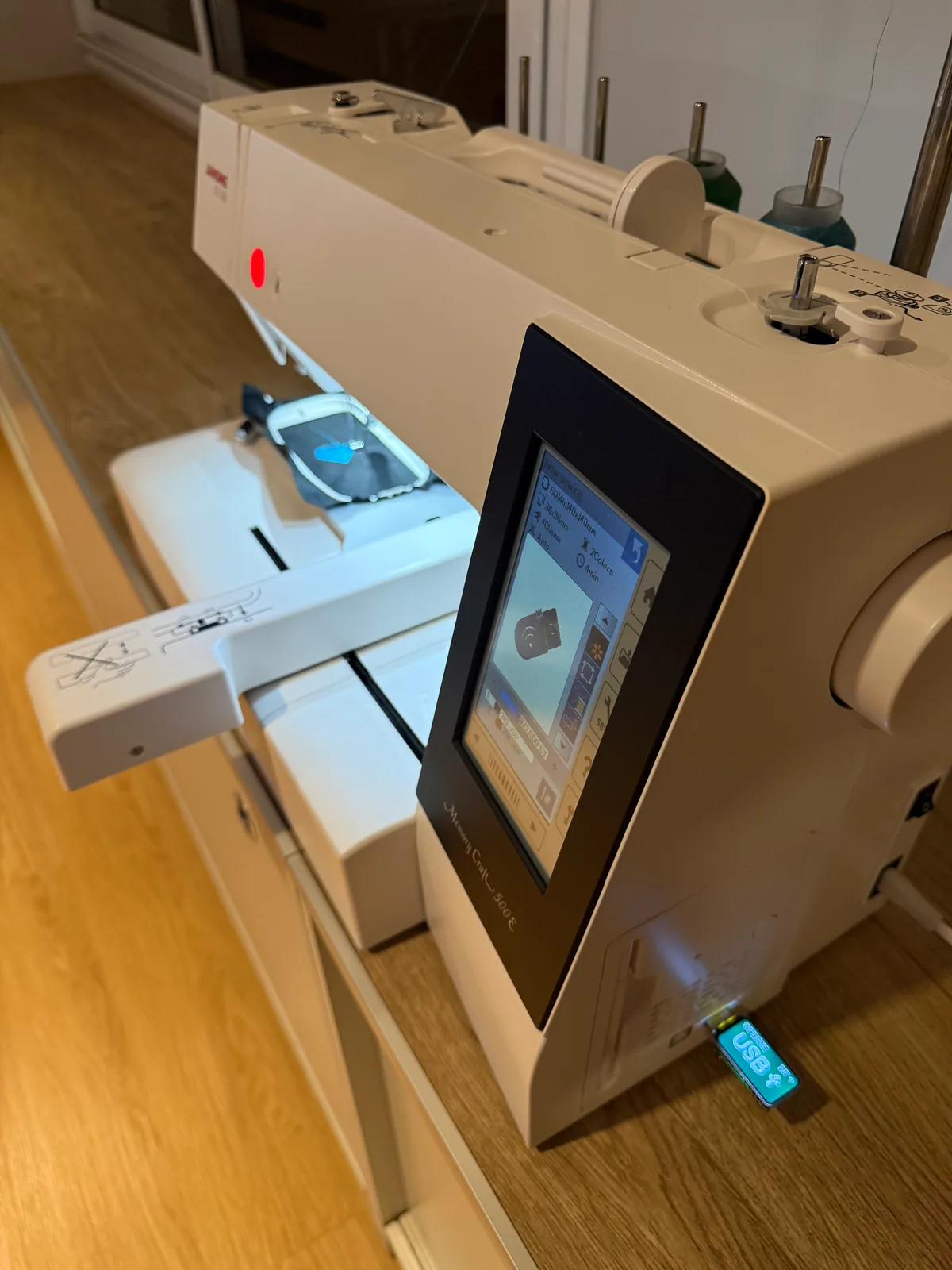 A Janome Memory Craft 500E with the WiFiDrive in its USB port, in USB mode, an embroidery hoop on the arm